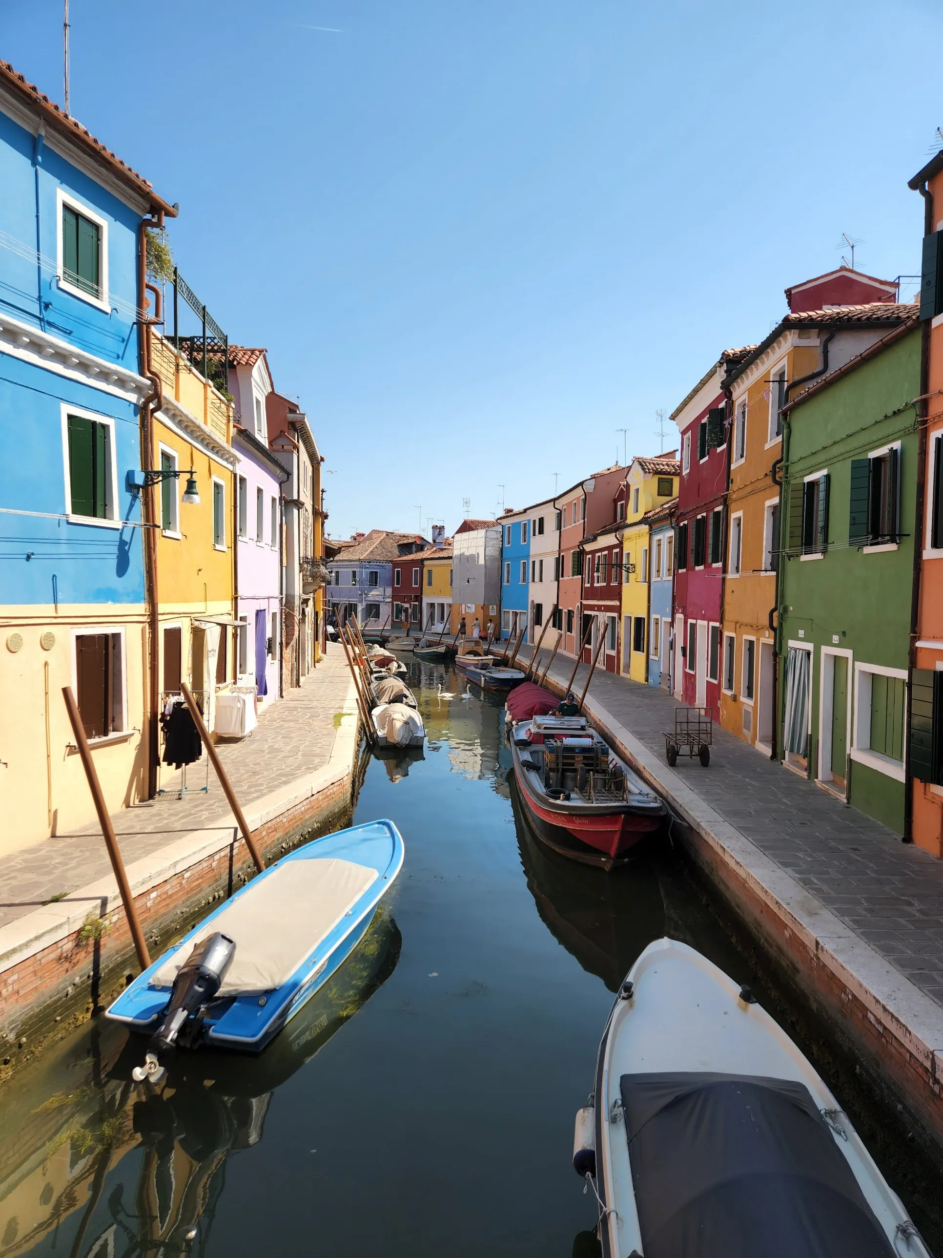 Colorful houses and boats along a canal in Burano, Italy